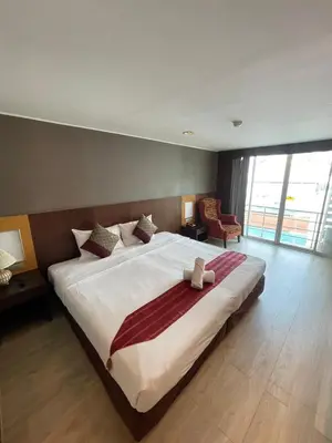 a bedroom with a large white bed with a robe on it at Tori crown hotel in Bangkok