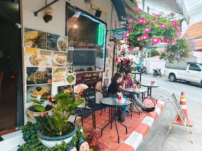 two people sitting at tables outside of a restaurant at Rhythm of life guesthouse 56 in Bangkok