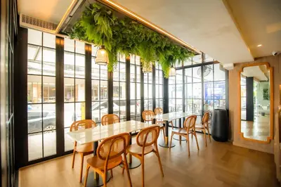 a dining room with tables and chairs and windows at THEE Bangkok by TH District in Bangkok