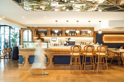 a woman walking past a bar in a restaurant at THEE Bangkok by TH District in Bangkok