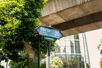 a blue street sign on a pole in front of a building at THEE Bangkok by TH District in Bangkok