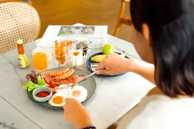 a woman sitting at a table with a plate of food at THEE Bangkok by TH District in Bangkok