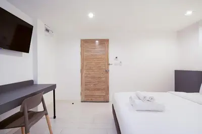 a room with a bed and a desk and a door at The Urban Oasis in Bangkok