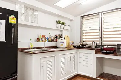 a kitchen with white cabinets and a black refrigerator at Suttisan \u5730\u94c1\u53e3\u4e8c\u5c42\u72ec\u680b\u82b1\u56ed\u522b\u5885 \u4e94\u5367\u5ba4\u4e09\u536b in Bangkok