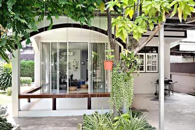 a pivot house with glass walls and trees at Suttisan \u5730\u94c1\u53e3\u4e8c\u5c42\u72ec\u680b\u82b1\u56ed\u522b\u5885 \u4e94\u5367\u5ba4\u4e09\u536b in Bangkok