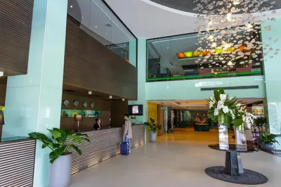 a lobby of a shopping mall with a woman with a suitcase at Jazzotel Bangkok in Bangkok