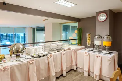 a dining room with tables with white tablecloths and plates at Prom Hotel in Bangkok