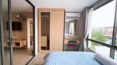 a bedroom with a bed and a desk and a window at Resort Style Room Suksawat 64 Bangkok ND in Ban Tha Hin