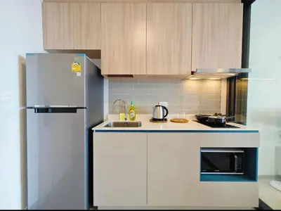 a kitchen with white cabinets and a refrigerator at Thanon Phaya in Bangkok