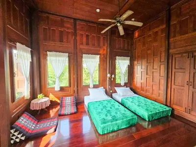 two beds in a room with wooden walls and windows at The Thai House Homestay & Thai Cooking Experiences in Ban Bang Sano