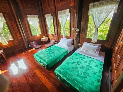 two beds sitting in a room with windows at The Thai House Homestay & Thai Cooking Experiences in Ban Bang Sano