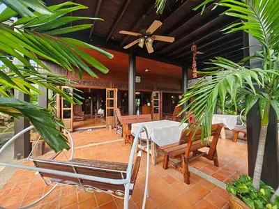 a patio with tables and chairs and a ceiling fan at The Thai House Homestay & Thai Cooking Experiences in Ban Bang Sano