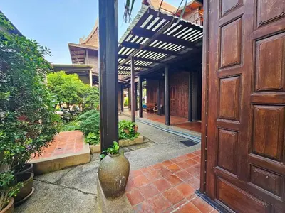an open wooden door with a vase sitting in a courtyard at The Thai House Homestay & Thai Cooking Experiences in Ban Bang Sano