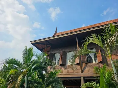 a wooden house with palm trees in front of it at The Thai House Homestay & Thai Cooking Experiences in Ban Bang Sano