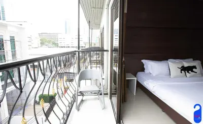 a balcony with a bed and a chair on it at Bed By City Hotel in Bangkok