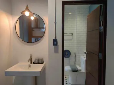 a bathroom with a sink and a mirror and a toilet at N5 Ratchawong Hostel in Bangkok