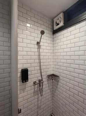 a shower in a bathroom with white tile walls at N5 Ratchawong Hostel in Bangkok