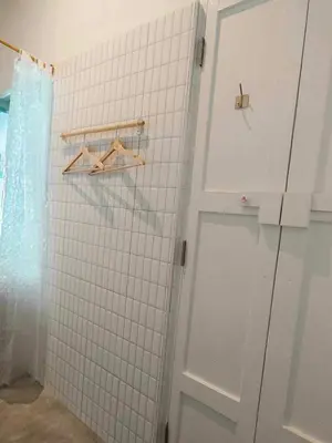 a bathroom with a white tiled wall and a door at Mr Black & Ms White -Self Check in accommodation in Pom Prap