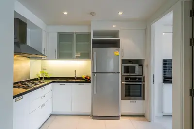 a kitchen with white cabinets and a stainless steel refrigerator at Destiny55 Thonglor Apartment in Bangkok