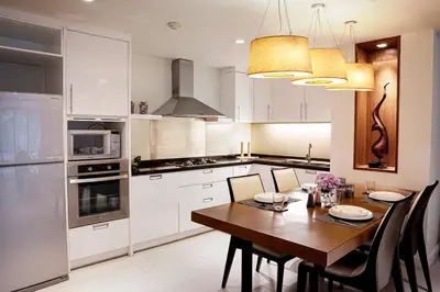 a kitchen with a wooden table and white cabinets at Destiny55 Thonglor Apartment in Bangkok