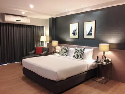 a bedroom with a large white bed and a chair at Alt Hotel Nana by UHG in Bangkok