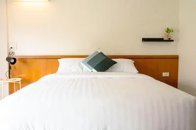 a white bed with a book on top of it at Alley & Pier in Bangkok