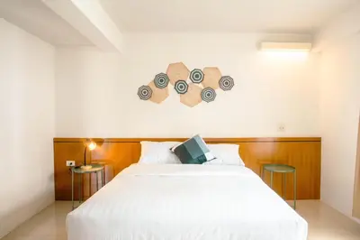 a bedroom with a white bed and a clock on the wall at Alley & Pier in Bangkok