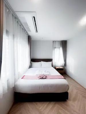 a bedroom with a bed with white walls and windows at SO Zen Hotel Silom Bangkok in Bang Rak