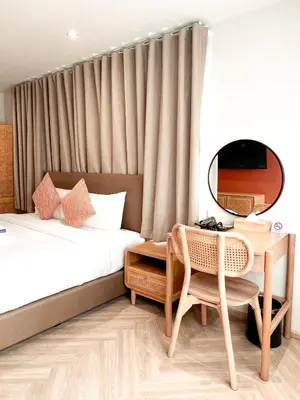 a hotel room with a bed and a table and a mirror at SO Zen Hotel Silom Bangkok in Bang Rak