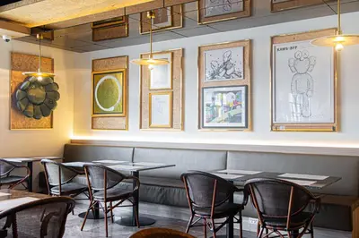 a restaurant with tables and chairs and pictures on the wall at Frame Hotel Bangkok in Bangkok