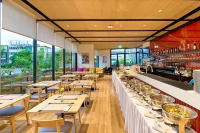 a restaurant with long tables and chairs and windows at MO Hotel Bangkok in Bangkok