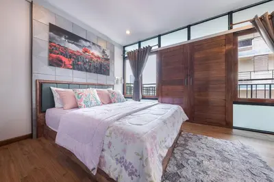 a bedroom with a large bed and a large window at Thananya Apartment in Amphoe Phra Khanong
