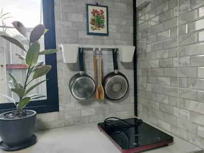 a kitchen with utensils hanging on a wall at Thananya Apartment in Amphoe Phra Khanong
