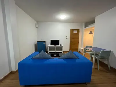 a blue couch in a living room with a table at Dao Jaras Fah Hometel ดาวจรัสฟ้าโฮมเทล in Bangkok