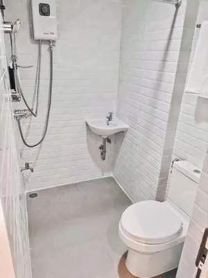 a white bathroom with a toilet and a sink at Jira19Hostel in Bangkok