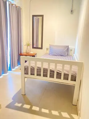 a white bed in a room with windows at Jira19Hostel in Bangkok