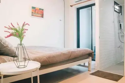 a room with a bed and a table with a plant at Jira19Hostel in Bangkok