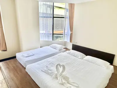 two beds with white sheets with a bow on them at ABC SO Hotel Bangkok in Bangkok