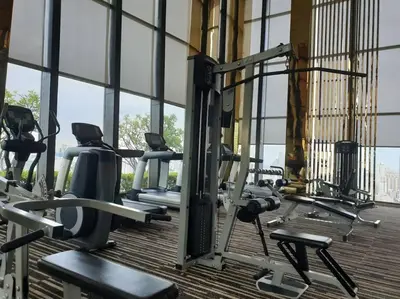 a gym with rows of tread machines in front of windows at Grand Modern 2BR - Ultra Fast WiFi - Phrom Phong in Bangkok