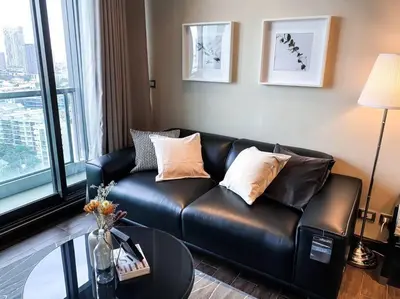 a black leather couch in a living room with a table at Grand Modern 2BR - Ultra Fast WiFi - Phrom Phong in Bangkok