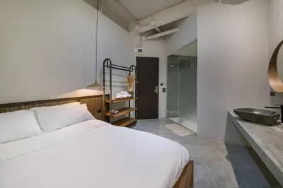 a bedroom with a bed and a bathroom with a sink at Siam Shelter Bangkok in Bangkok