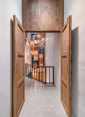 a hallway with two wooden doors and a balcony at Siam Shelter Bangkok in Bangkok