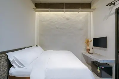 a bedroom with a white bed and a television at Siam Shelter Bangkok in Bangkok