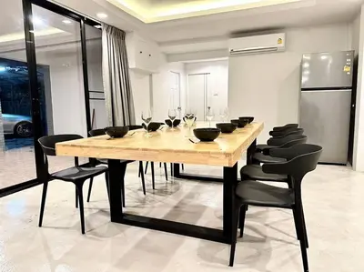 a dining room with a wooden table and black chairs at Number3 Poolvilla Bangkok in Lat Krabang