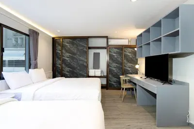 two beds in a room with a desk and a television at Capitel Rama 4 in Bangkok