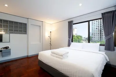 a bedroom with a white bed and a large window at Capitel Rama 4 in Bangkok