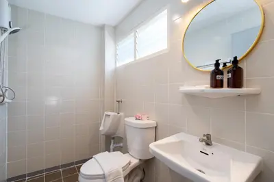 a bathroom with a toilet and a sink and a mirror at Capitel Rama 4 in Bangkok