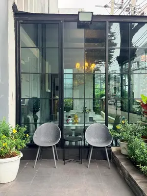 two chairs and a table on a patio with windows at Marigold Sukhumvit - Free Shuttle to BTS Bearing Station in Bangkok