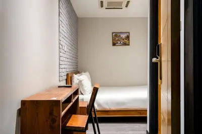 a small bedroom with a bed and a wooden desk at XX GO INN Sukhumvit-Bts Asoke-Phrom Phong โกอินน์ สุขุมวิท in Bang Kapi