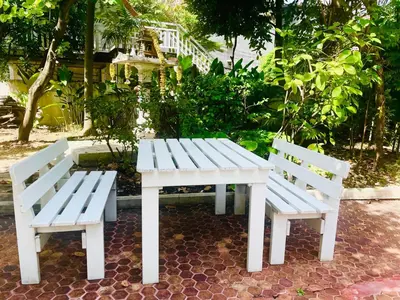 two white benches sitting next to a white table at The Backyard 28 in Khlong Toei
